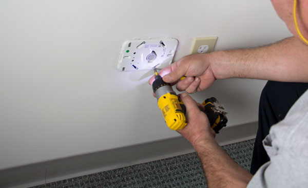 Man Installing MVR-300 Refrigerant Monitor in Hotel Room Wall